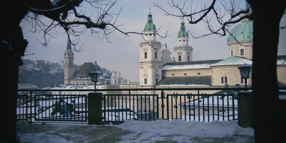 Snowy panorama of a square with trees overlooking Salzburg Cathedral in Austria
