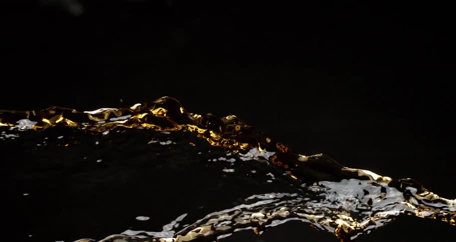 Extreme closeup of a liquid thrown into the air and falling in slow motion on a black background