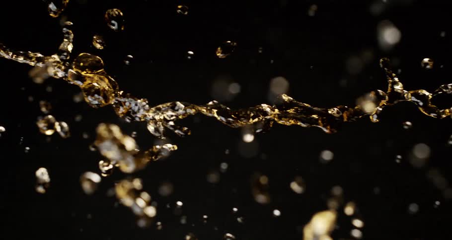 A splash of yellow liquid flies over a dark background