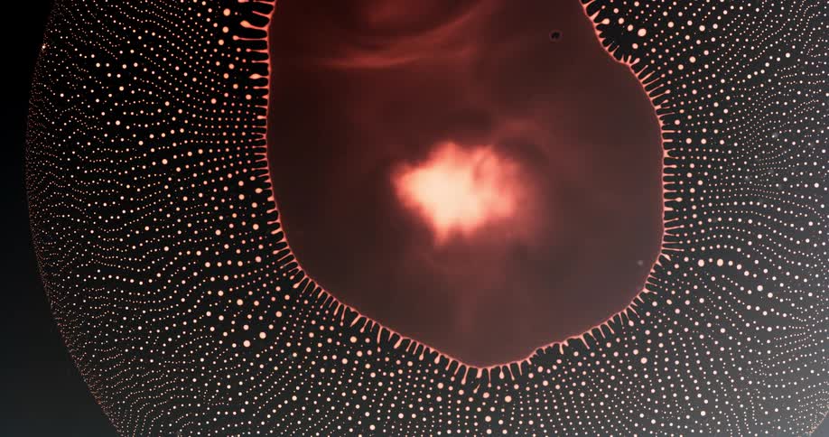 Extreme closeup of a bright reddish droplet collapsing and forming a pattern of small abstract polka dots