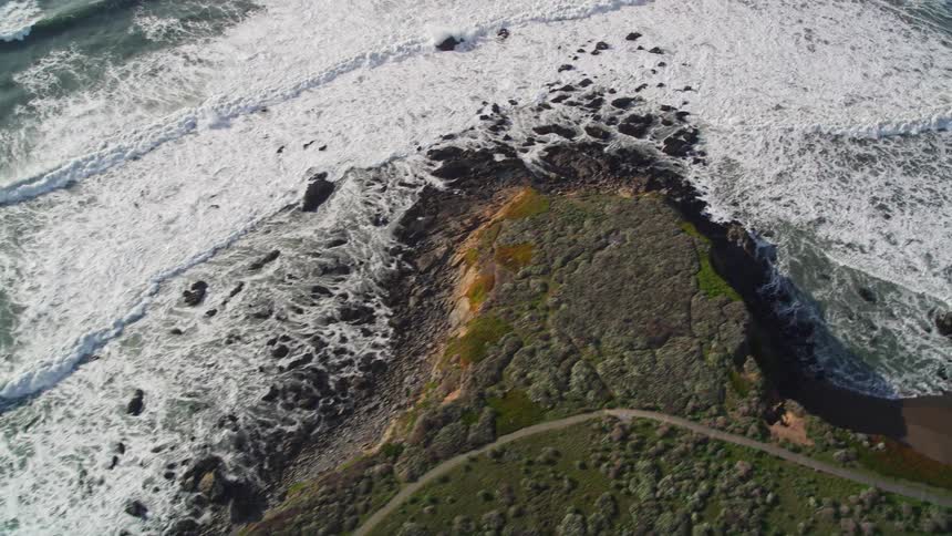 Aerial view of rocky coast and sea with foamy waves