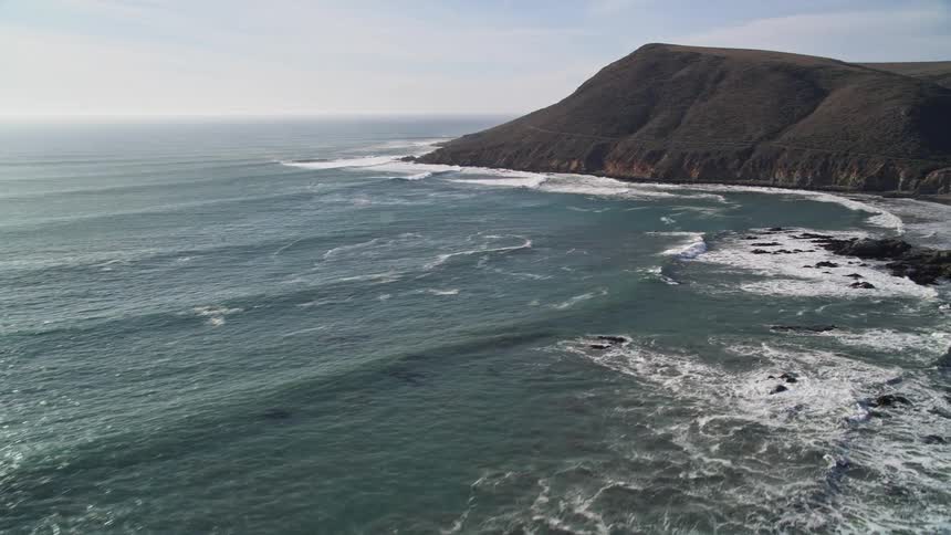 Panorama of the lush ocean with the reflection of the sun and the rocky coast that surrounds it