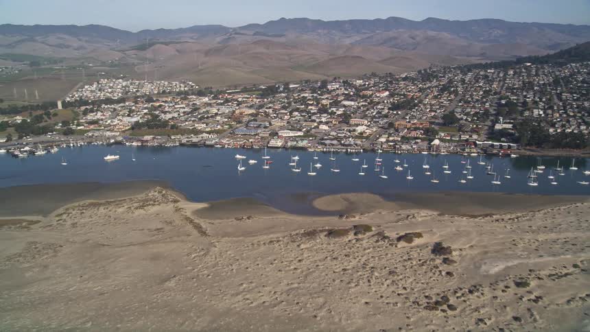 Aerial view of the sea with an urban city and mountains on the horizon