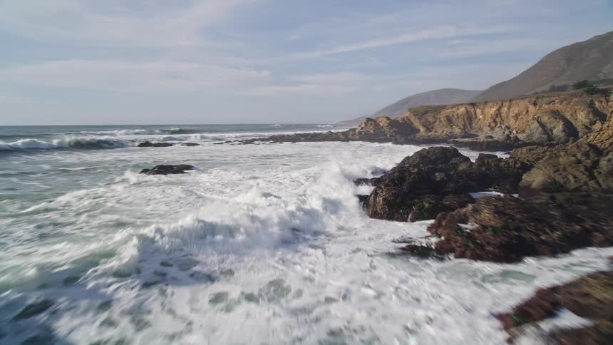Natural sea scenery with waves crashing on the rocks at the coast during the day