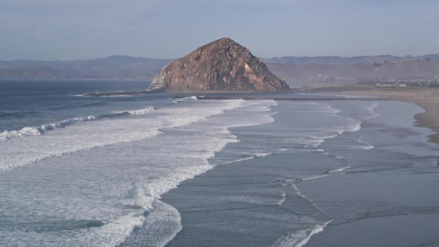 A big mountain sits on a coast near a rural community