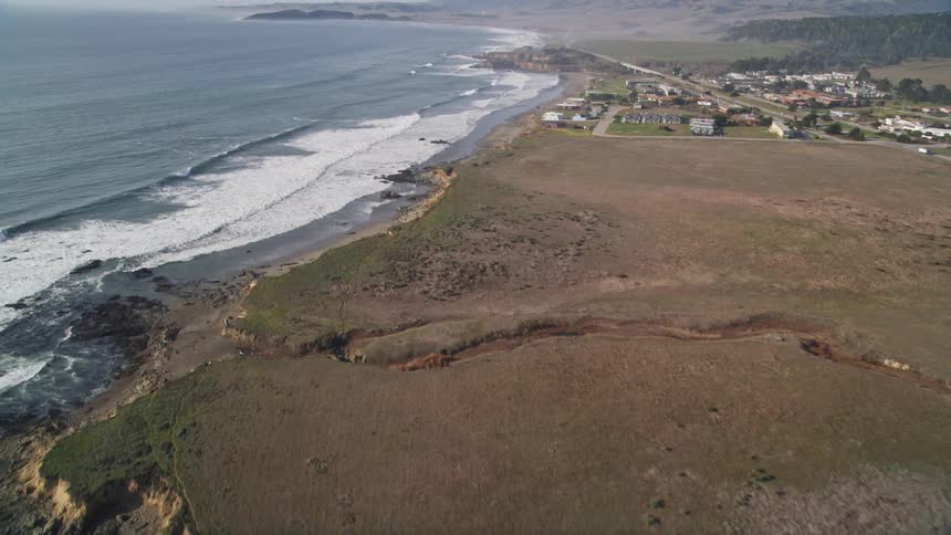 Waves crash against the shore near a rural community