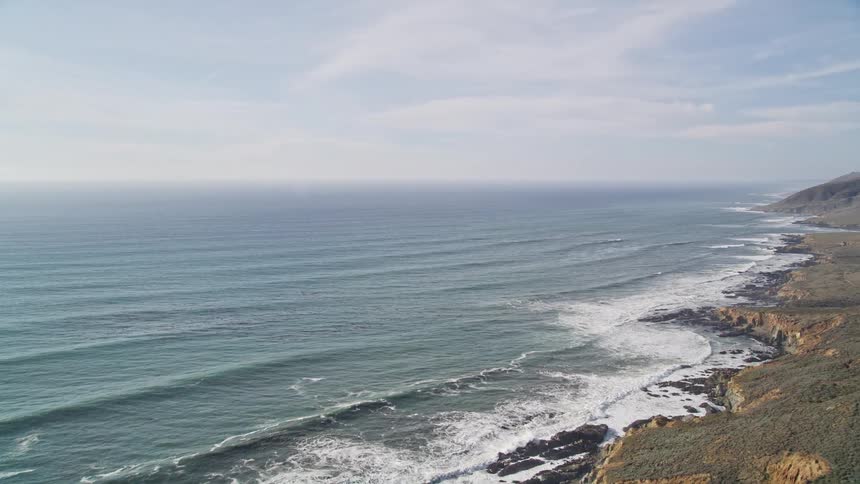 Aerial landscape of the vast sea surrounded by rocky mountains on a clear day