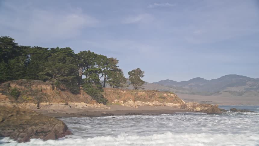 Coastline with calm ocean waters long pier and mountains in the background
