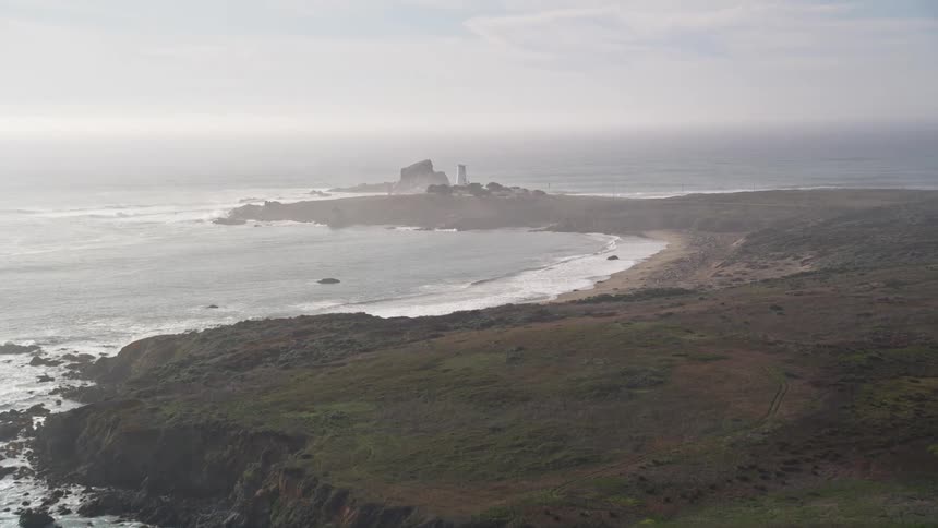 A lighthouse sits on an outgrowth of a coastline