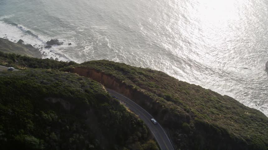 Cars driving on a road going over a coastal mountain
