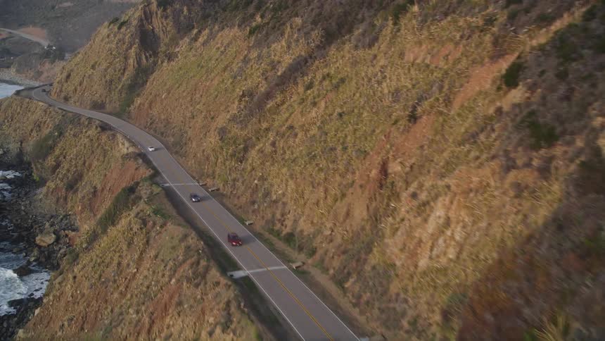 Cars drive down a coastal highway