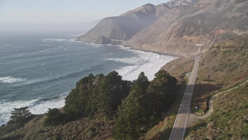 Aerial panorama of a long highway amid mountains and next to the sea