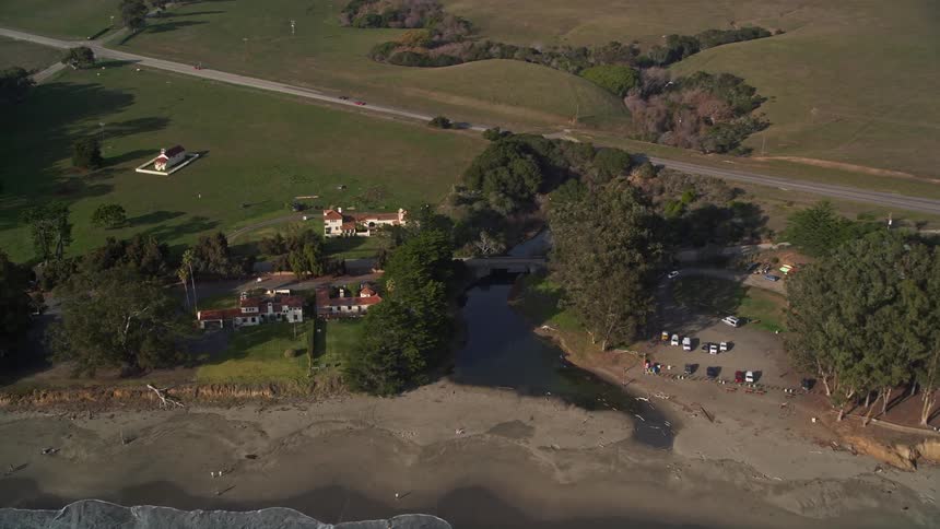 Aerial panorama of a beach next to highways in natural fields with mountains on the horizon