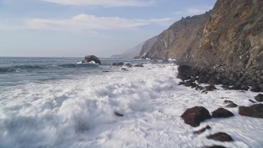 Waves crash against the mountains
