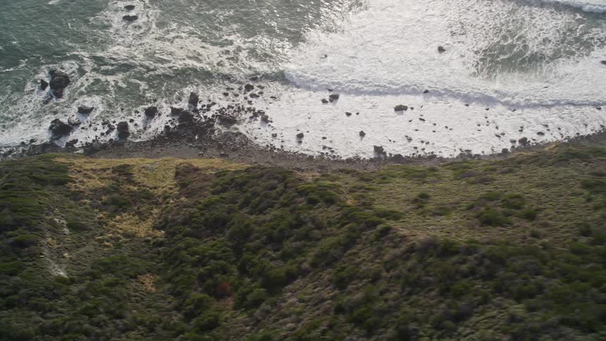 Waves crash against the steep mountain shore