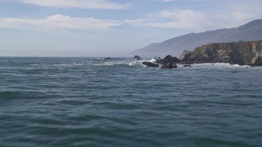Seascape with rocks and mountains on the horizon