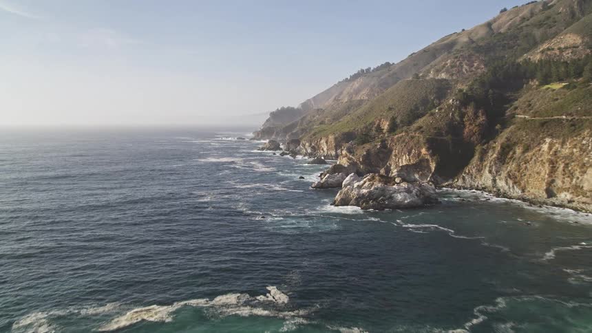 Waves crash against a rocky and mountainous shore
