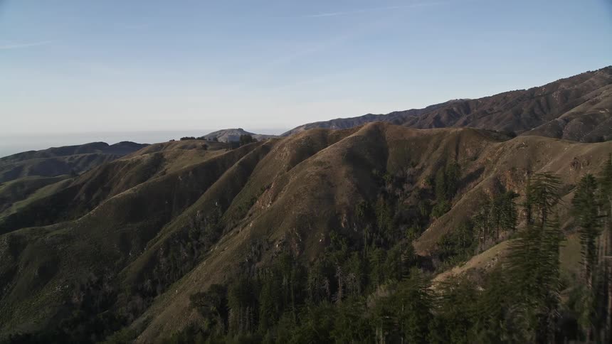 Aerial panorama of greenish mountain ranges on a blue sky day