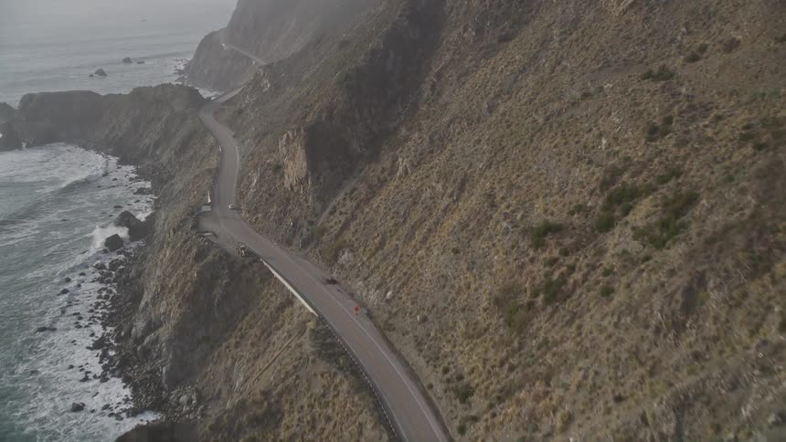 Aerial panorama of an extensive highway and a bridge on a seaside mountain cliff