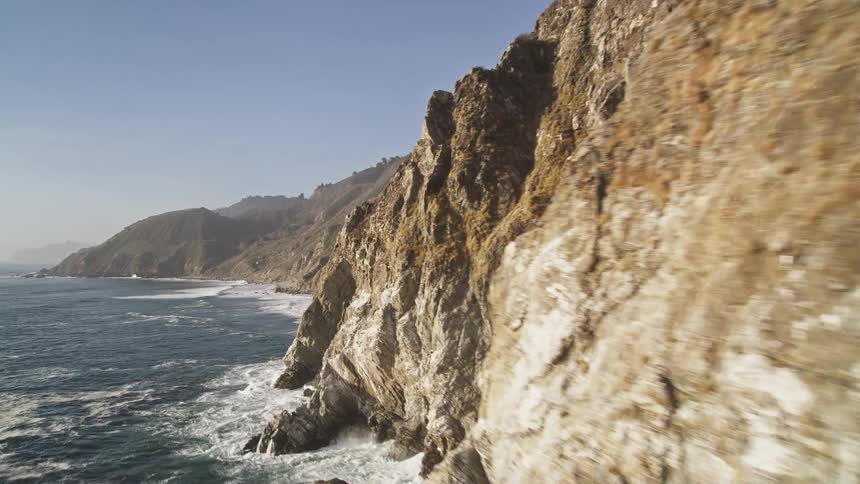 Waves crash against the mountains
