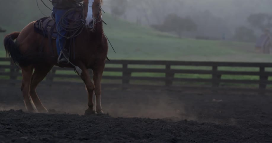 Man riding a horse in circles inside a pen
