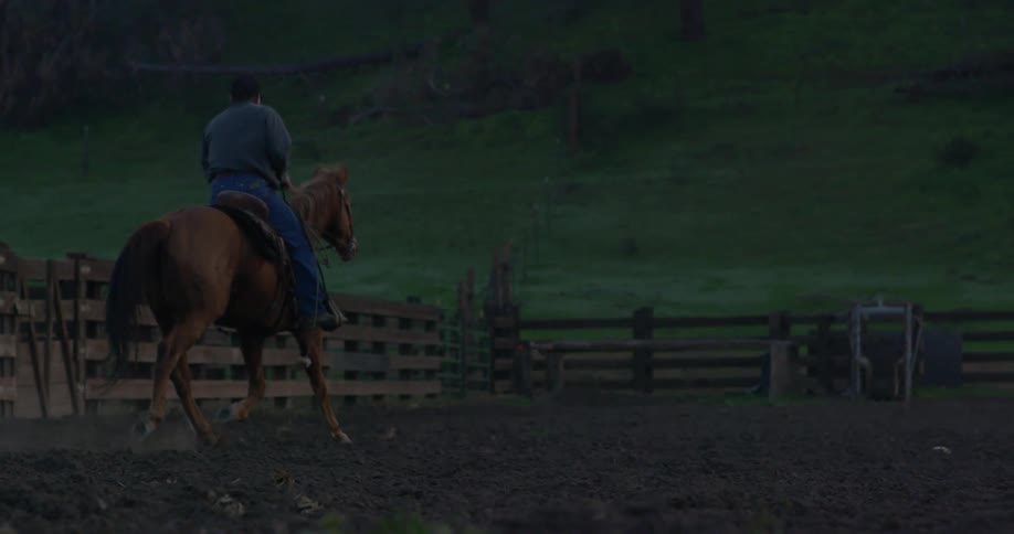 Person riding a horse in a coral on a ranch