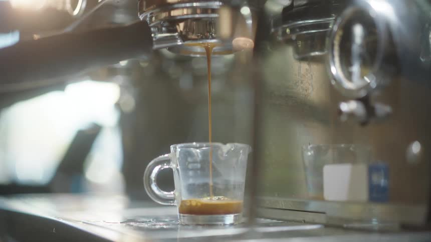 Machine serving cappuccino in a glass cup in a coffee shop