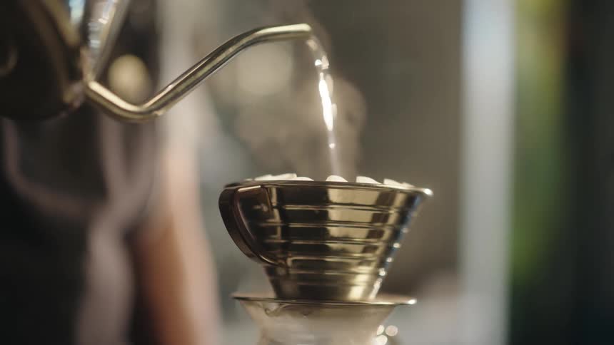 Spout of a kettle pouring water into a coffee filter