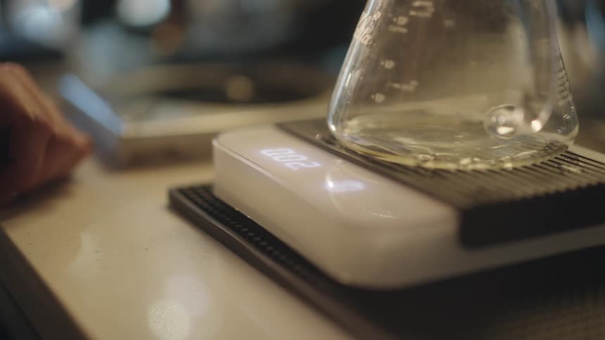 A mans hand preparing a carafe on top of a coffee decanting machine
