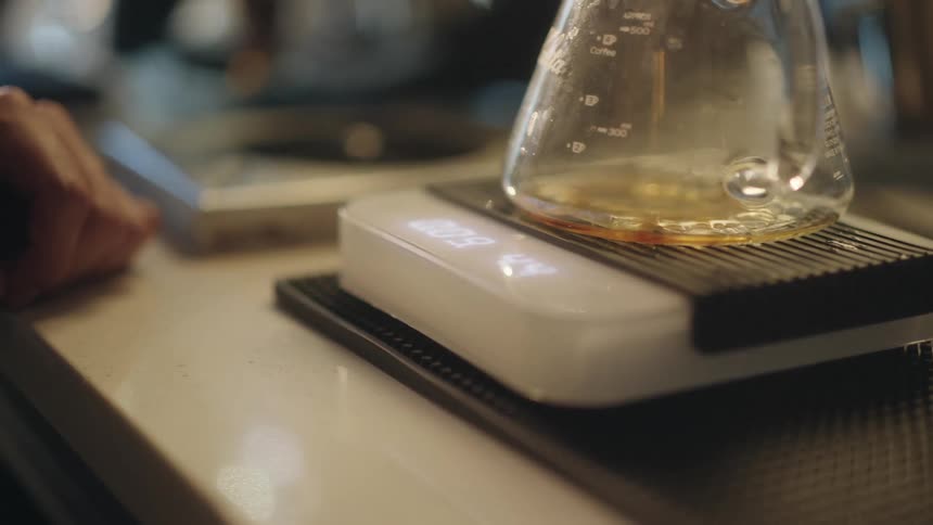 A person is making coffee using a pourover method and scale