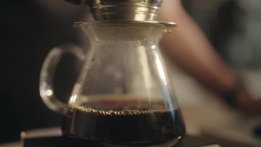 Coffee pot filling with coffee as a barista uses the pourover brewing method