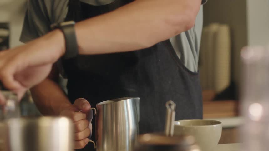 Man in an apron in a cafe preparing a coffee