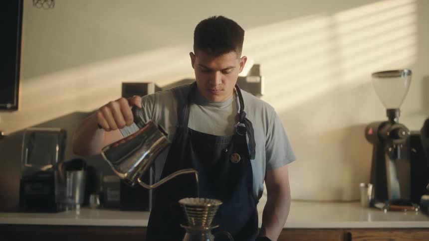A male barista uses the pourover method to brew coffee