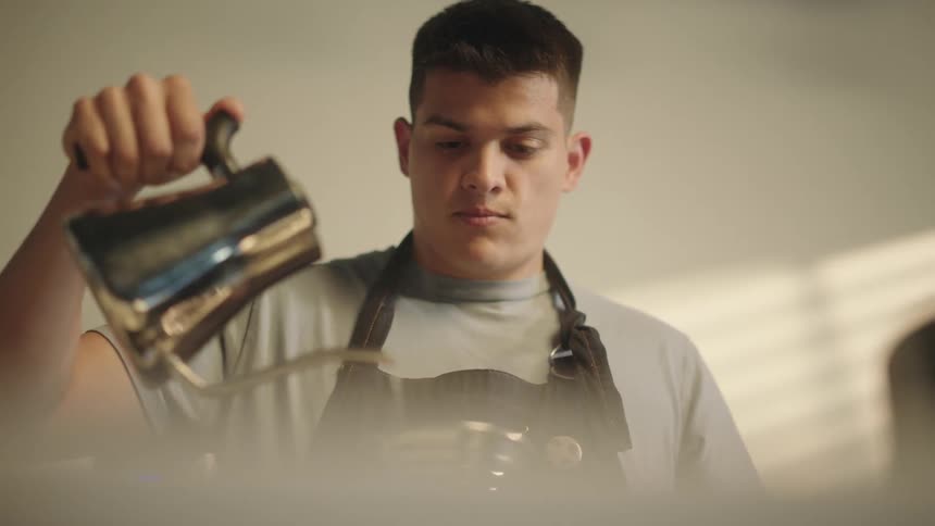 A man is pouring water from a teapot into another container