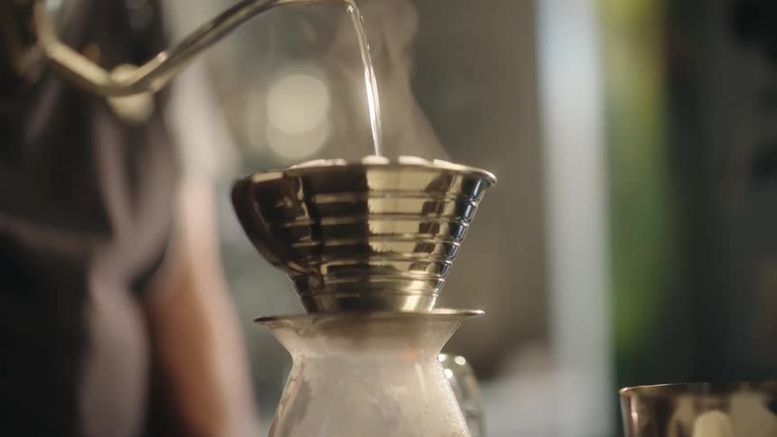 Closeup of a coffee filter and a person adding hot water