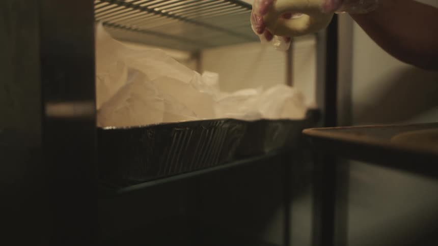 An employee removes bagels from a freezer