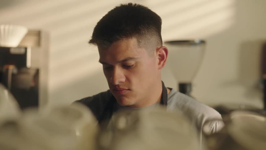 A barista preparing coffee and steam rises in front of him