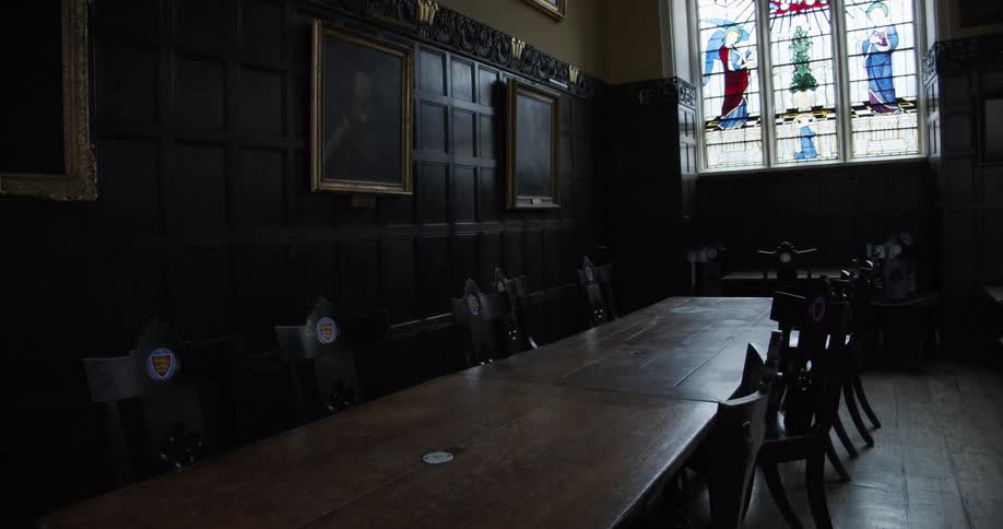 A huge black wooden table with several matching chairs with a logo
