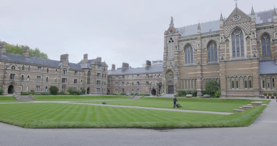 A worker mows the lawn of a large estate