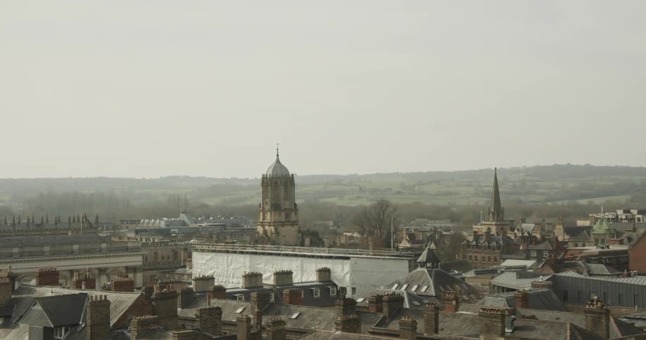 Birds fly over buildings near domed cathedral on a foggy day