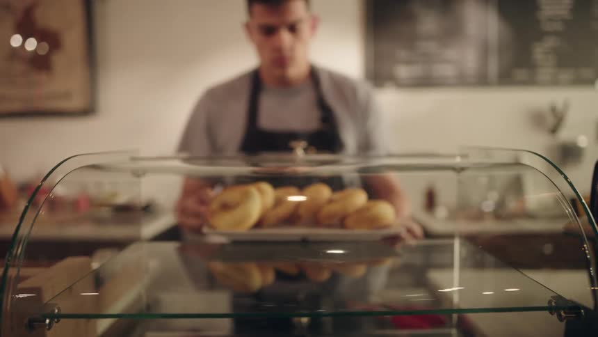 A man placing a tray of a round dessert into a glass dome