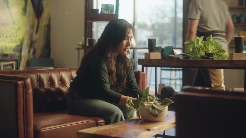 A waiter serves coffee to a customer seated on a leather couch