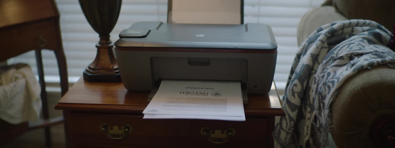 Printer printing documents on top of a bookshelf in a room