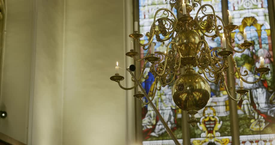 A chandelier with candles burning in a church