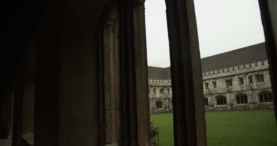 A building of ancient architecture with some pillars and in the center there is a green grass lawn