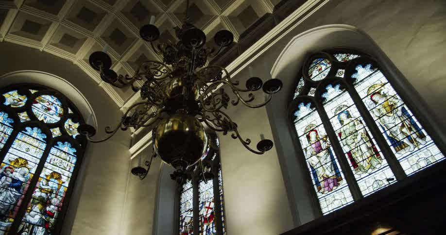 Chandeliers and stainedglass windows inside of the keble college chapel in oxford