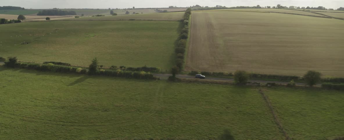 A car drives in a rural area of close together farm fields