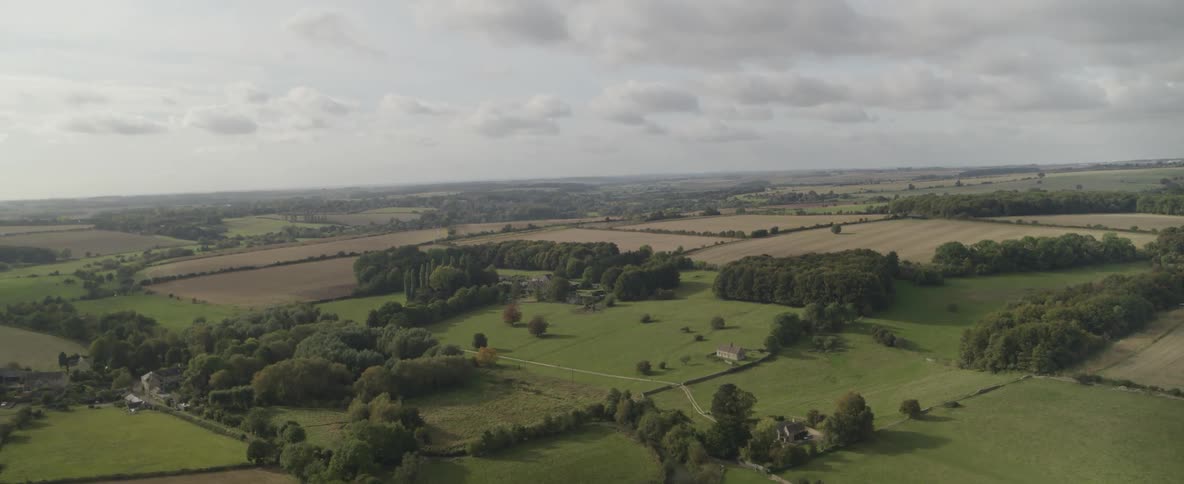 Aerial panorama of agricultural fields with rural houses in a morning sky with clouds