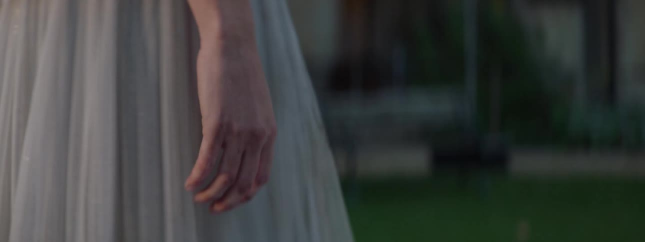 Closeup of a womans hands walking in a garden and adjusting her long dress