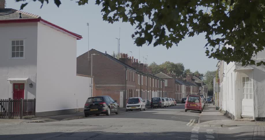 Suburban street with parked cars on a cloudless blue sky day